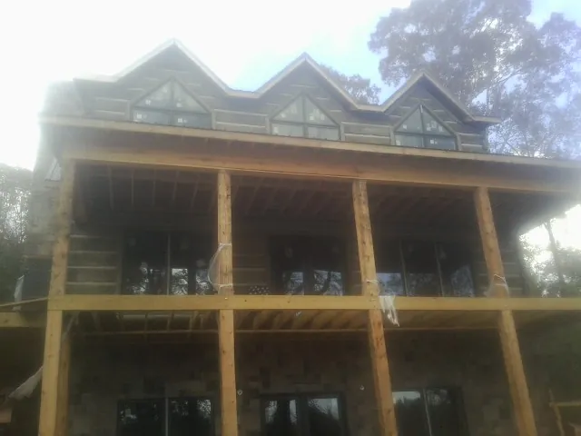 Dormers and porch framing on a large log home under construction — Roof Coating work by our crew in Broadway