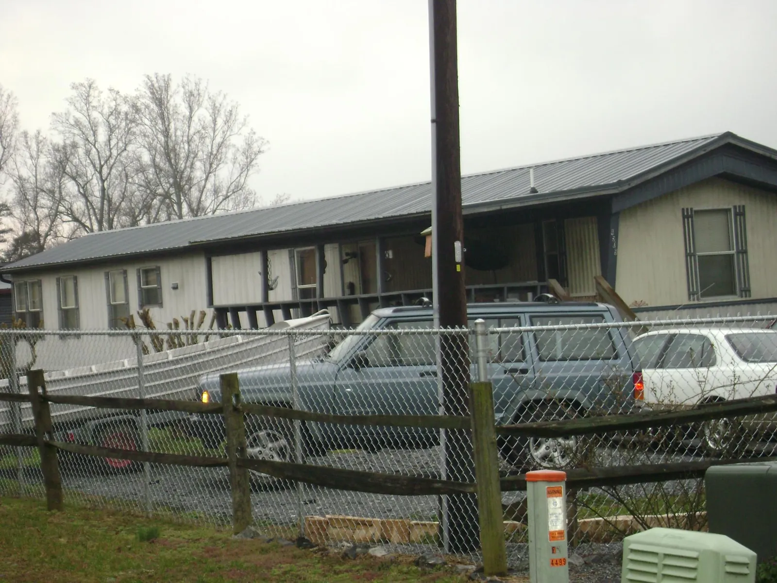 Dark metal roof on a long single story building behind a chain link fence in Broadway