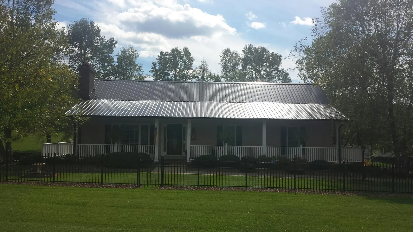 Gray metal roof on a brick ranch with a full width front porch — Gutter Guard Installation work by our crew in Broadway